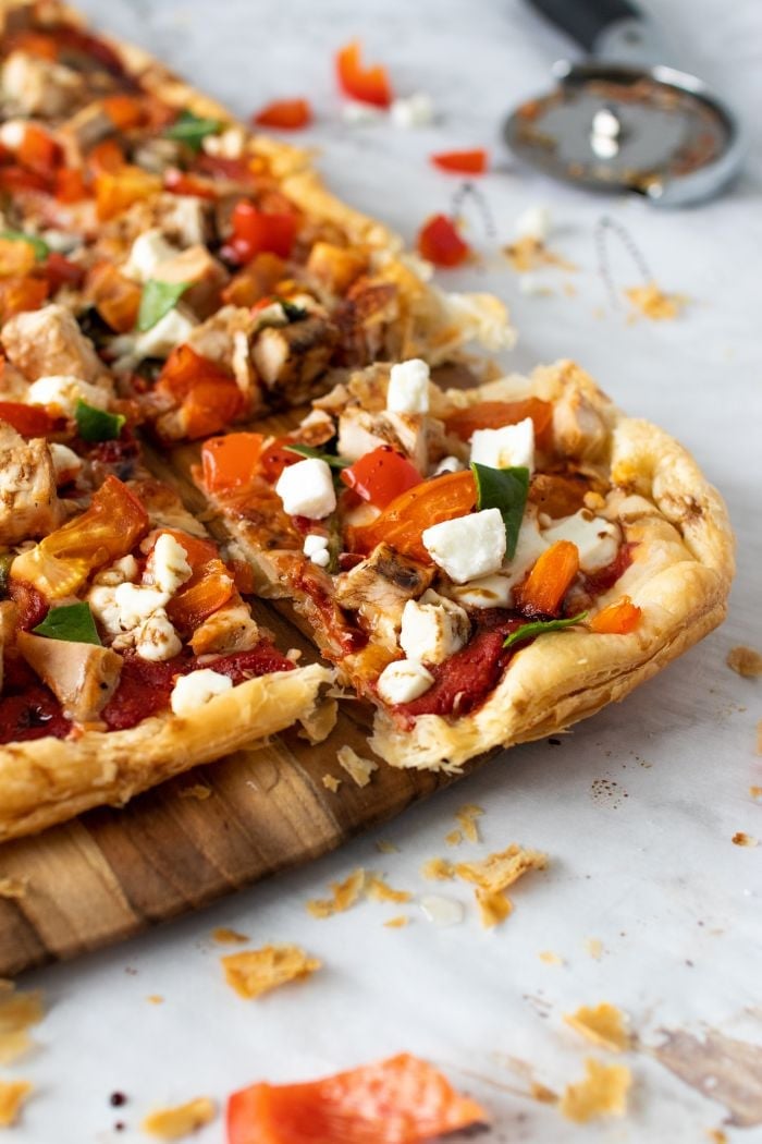 Puff pastry pizza is shown on a wooden cutting board
